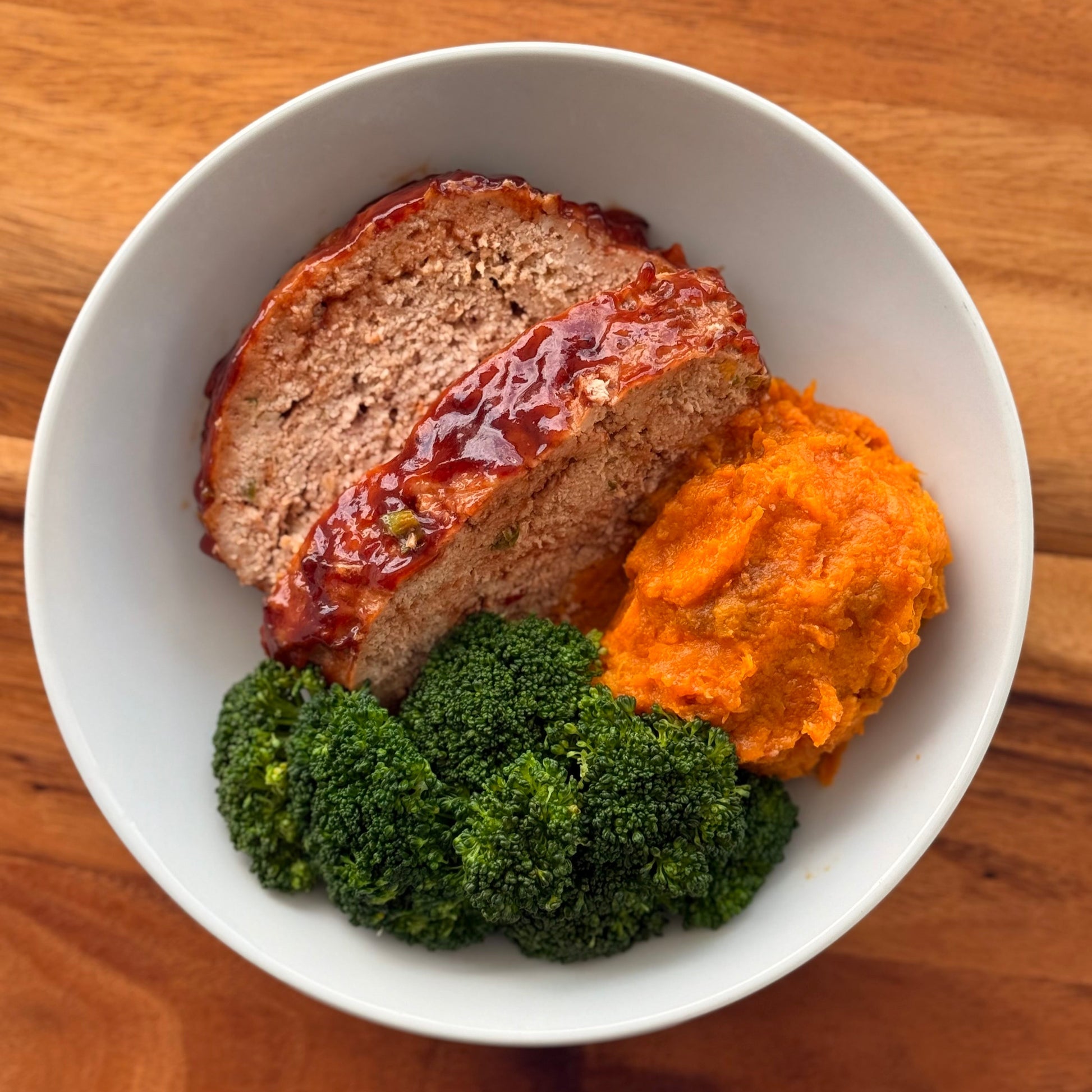 Sliced meatloaf with mashed sweet potatoes and broccoli.
